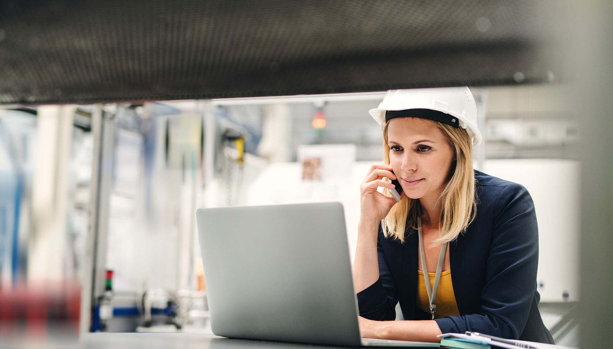 Woman wearing hard hat on computer.